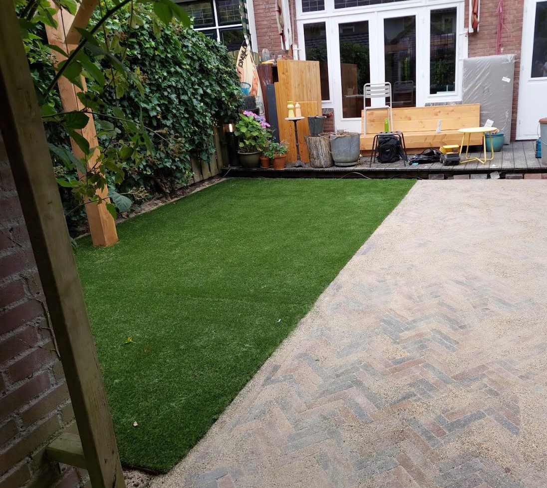 Achtertuin met gazon, visgraatbestrating en pergola
