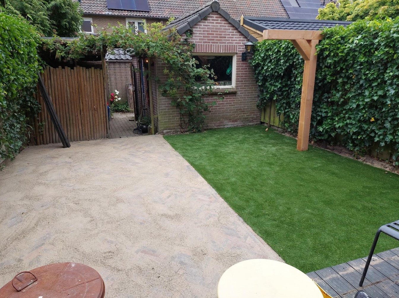 Achtertuin met gazon, pergola en strak terras