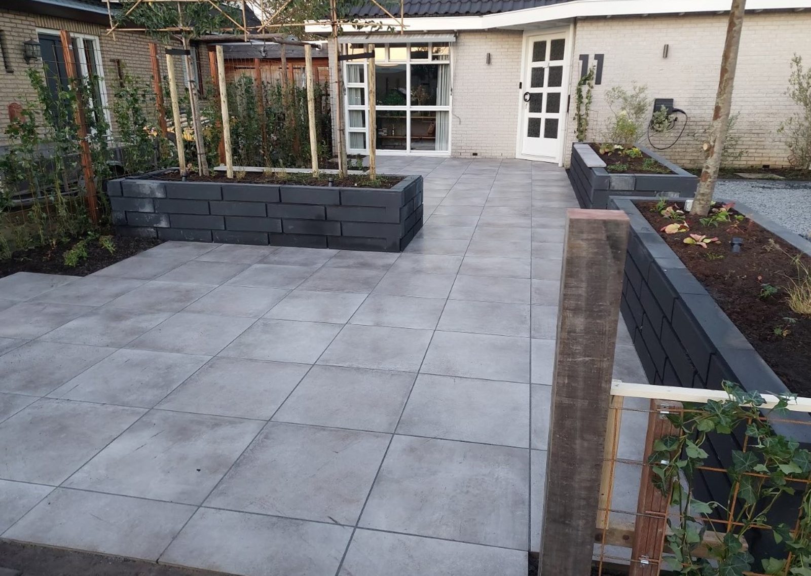 Ruim terras met keramische tegels en cortenstalen plantenbakken